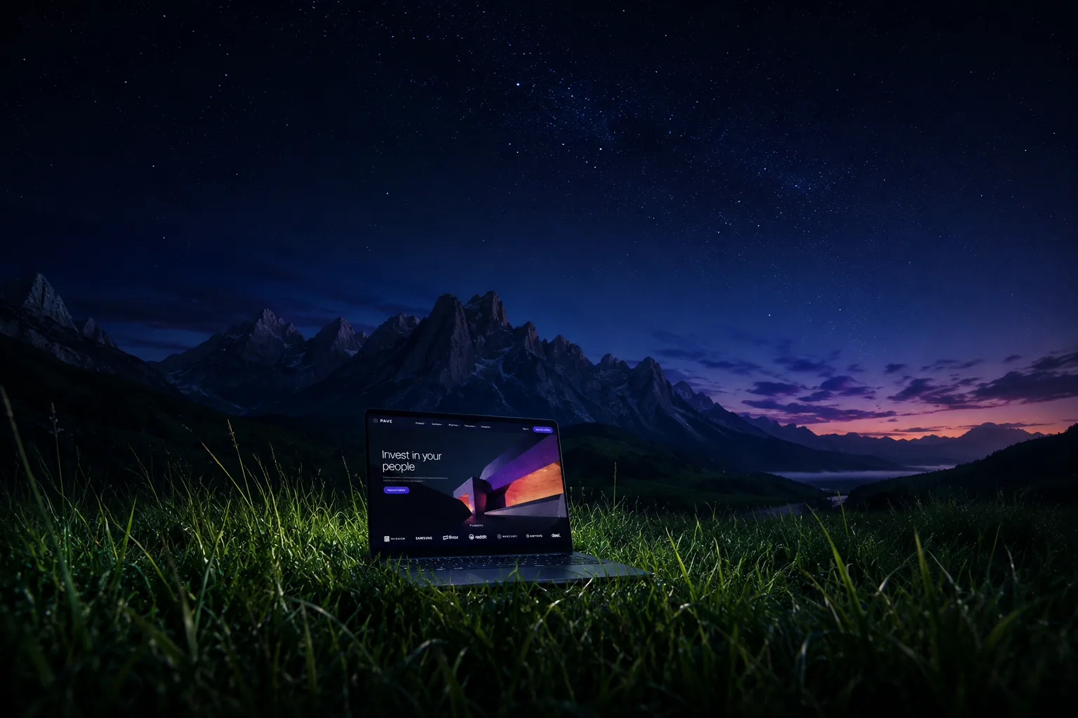 A laptop showing a finished website, standing in a mountain meadow under a night sky
